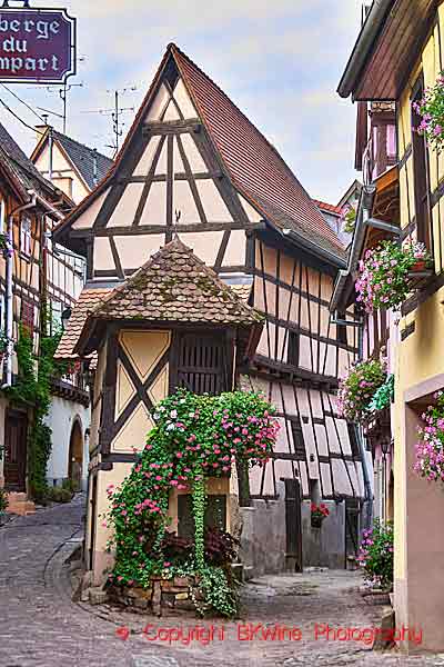 A narrow street with a half-timbered house with flowers in Eguisheim, Alsace
